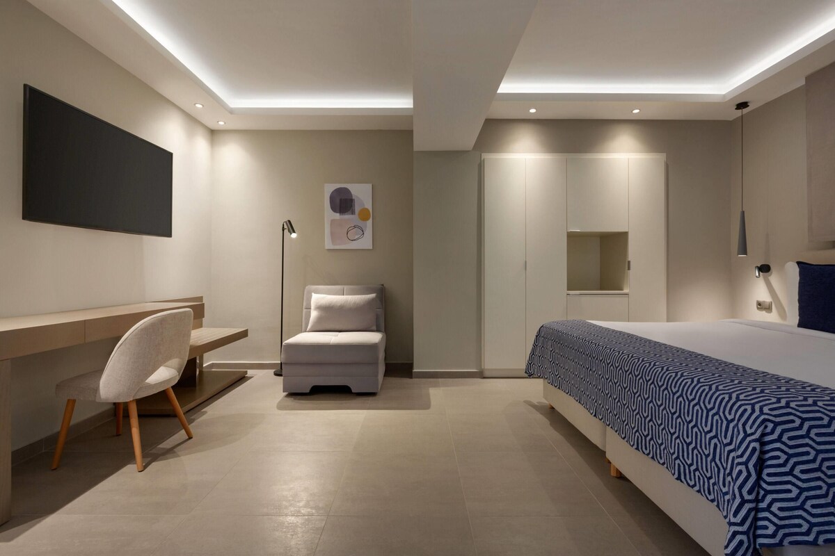 A modern bedroom with a bed, desk, chair, and a wardrobe.