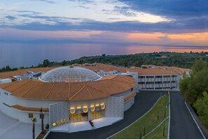 A building with a dome and a circular structure, surrounded by a parking area and greenery. - Ajul Luxury Hotel & Spa Resort Registry Collection (Kassandra)