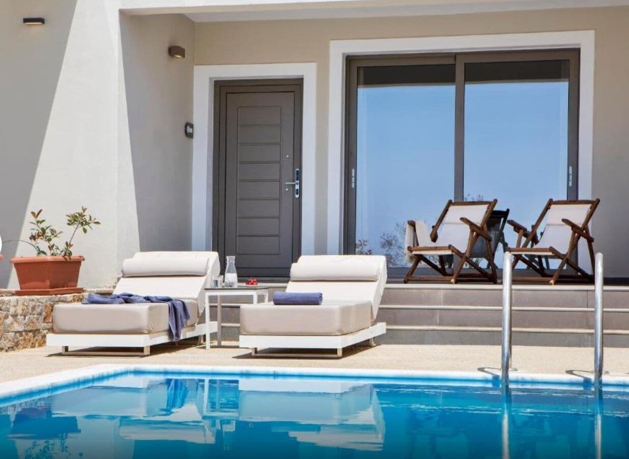 A poolside area with lounge chairs, a door, and large windows.