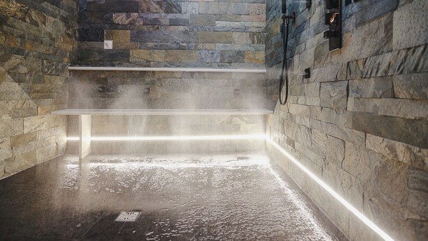 A steam room with stone walls and a wet floor, indicating a wet environment. - Incentro Domus (Polignano a Mare)
