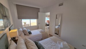 Une chambre d’hôtel avec deux lits, une grande fenêtre, un miroir et une vue sur l’espace extérieur.