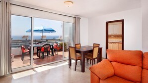 A balcony with a table and chairs, a sliding glass door, and a view of the sea. - Alfresco Stays Mijas Costa Blue Haven (Mijas Costa)