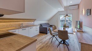 Une cuisine moderne avec un plan de travail en bois, un coin repas avec une table et des chaises, et un canapé gris.