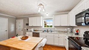 A kitchen with white cabinets, a wooden countertop, a built-in oven, and a microwave. - Perfect Guntersville Retreat Near Tennessee River! (Guntersville)