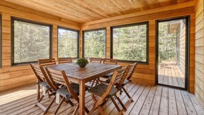 A wooden interior with a round table and chairs, large windows, and a view of trees. - Hôtel à la maison - Luxe Ô nature (Saint Come)