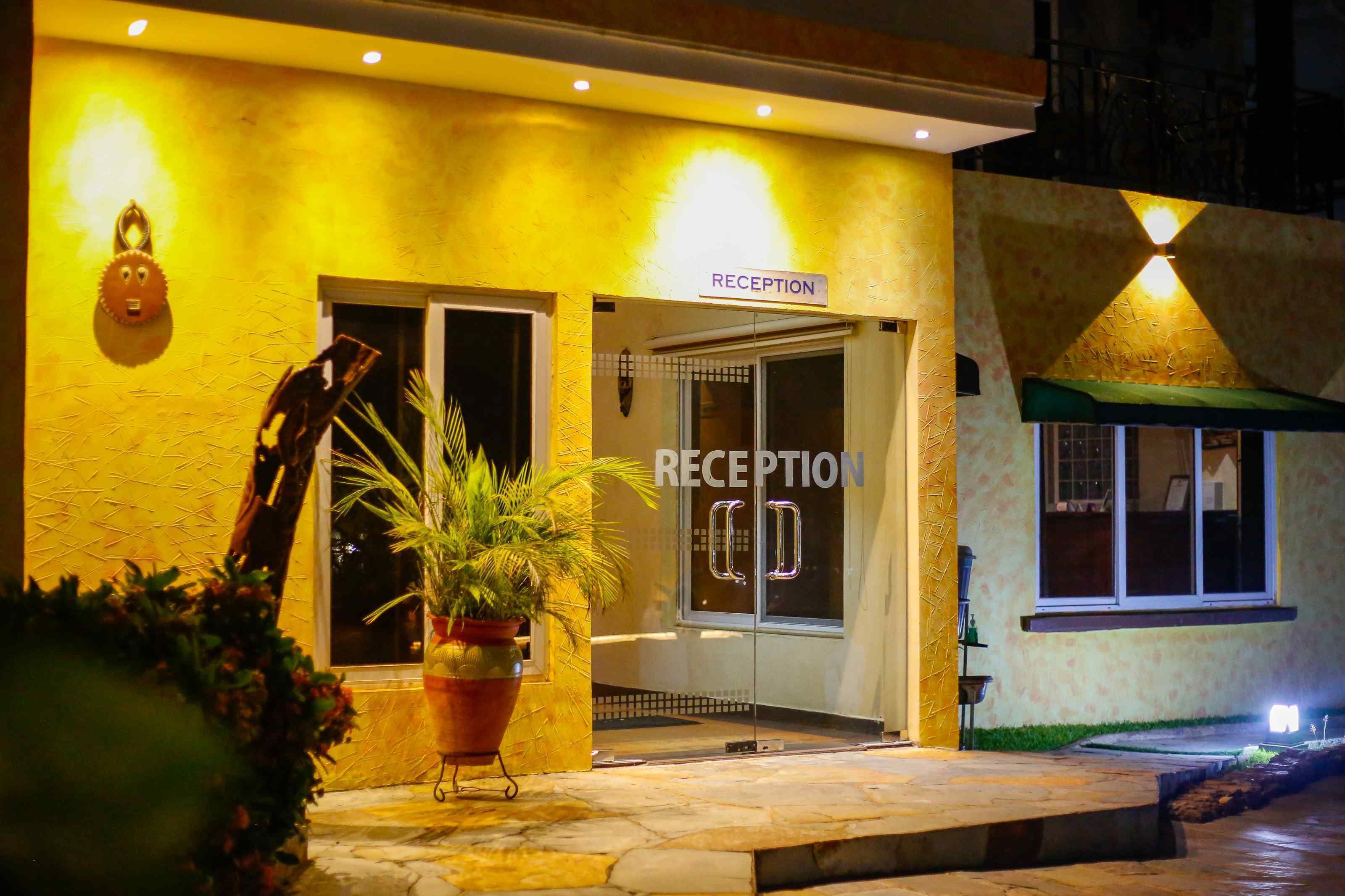 A reception area with a sign, a potted plant, and a unique wall decoration.