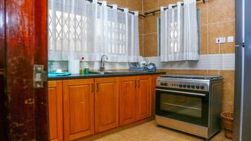 Una cocina con armarios de madera, estufa de acero inoxidable y salpicadero de azulejos.