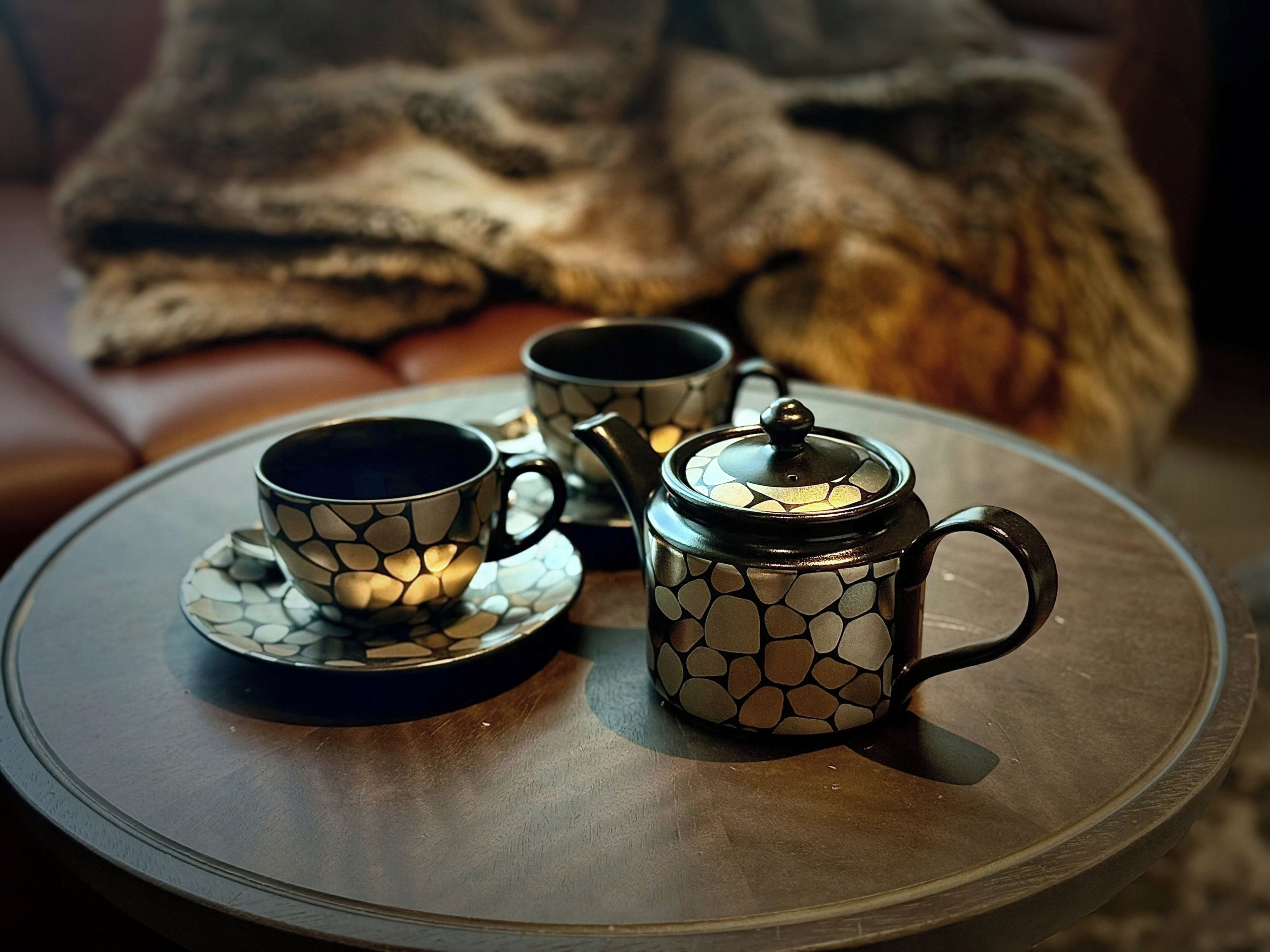 Une table avec une théière, deux tasses et une soucoupe.
