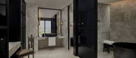 A modern bathroom with a large bathtub, a shower, and a sink area.