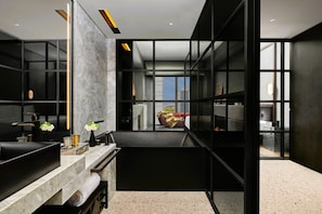 Une salle de bain moderne avec un grand miroir, des meubles de couleur noire et une vue sur le paysage urbain, visible à travers une porte en verre.