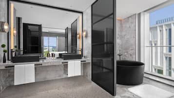 Een moderne badkamer met een dubbele wastafel, een grote spiegel en een zwart bad.