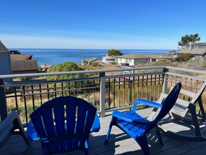 Enjoy the ocean view from this deck with two Adirondack chairs.