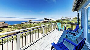 Une terrasse avec des chaises bleues donnant sur un paysage côtier.