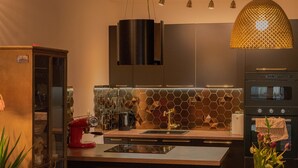 Eine moderne Küche mit einer zentralen Kochinsel, Edelstahlgeräten und einer einzigartigen, sechseckigen Spritzschutzwand.