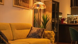 Ein Wohnzimmer mit einem gelben Sofa, einem Leopardenmuster-Kissen, einem runden Couchtisch und einer Stehlampe.