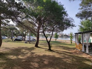 Enjoy serene lake views from a covered seating area amidst lush trees.
