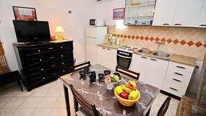 Una cocina compacta con mesa de comedor, microondas, refrigerador, estufa y lavaplatos.