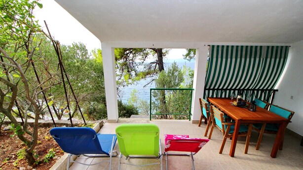 Un espacio de estar al aire libre cubierto, con una mesa y sillas, con vista a un cuerpo de agua.
