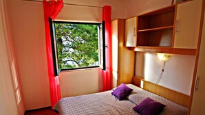 A bedroom with a bed, a window with red curtains, a headboard, and a wall-mounted shelf. - Apartments Sunset - Two Bedroom Apartment with Terrace and Sea View (Blato)