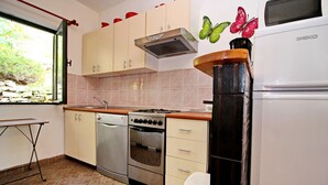 A kitchen with a stove, oven, and microwave, along with cabinets and a window. - Apartments Sunset - Two Bedroom Apartment with Terrace and Sea View (Blato)