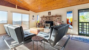 Ein modernes Wohnzimmer mit Kamin, Ledersofas, einem Couchtisch und großen Fenstern mit Blick auf die Stadt.