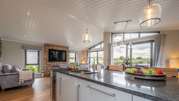Una cucina moderna con una grande isola, elettrodomestici integrati e un camino in pietra.
