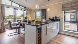 Una cucina moderna con isola centrale, ampie finestre e luci a sospensione.
