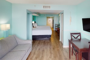 A hotel room with a bed, a desk, a chair, a TV, and a couch.