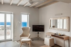 Enjoy the serene sea views from the comfort of your room, featuring a large window, plush armchair, and flat-screen TV.