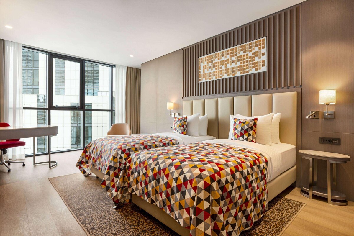 Une chambre d’hôtel moderne avec un grand lit, un bureau et une vue sur la ville.