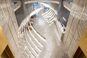 Un intérieur moderne avec un plafond incurvé, des murs en marbre et un espace salon central.