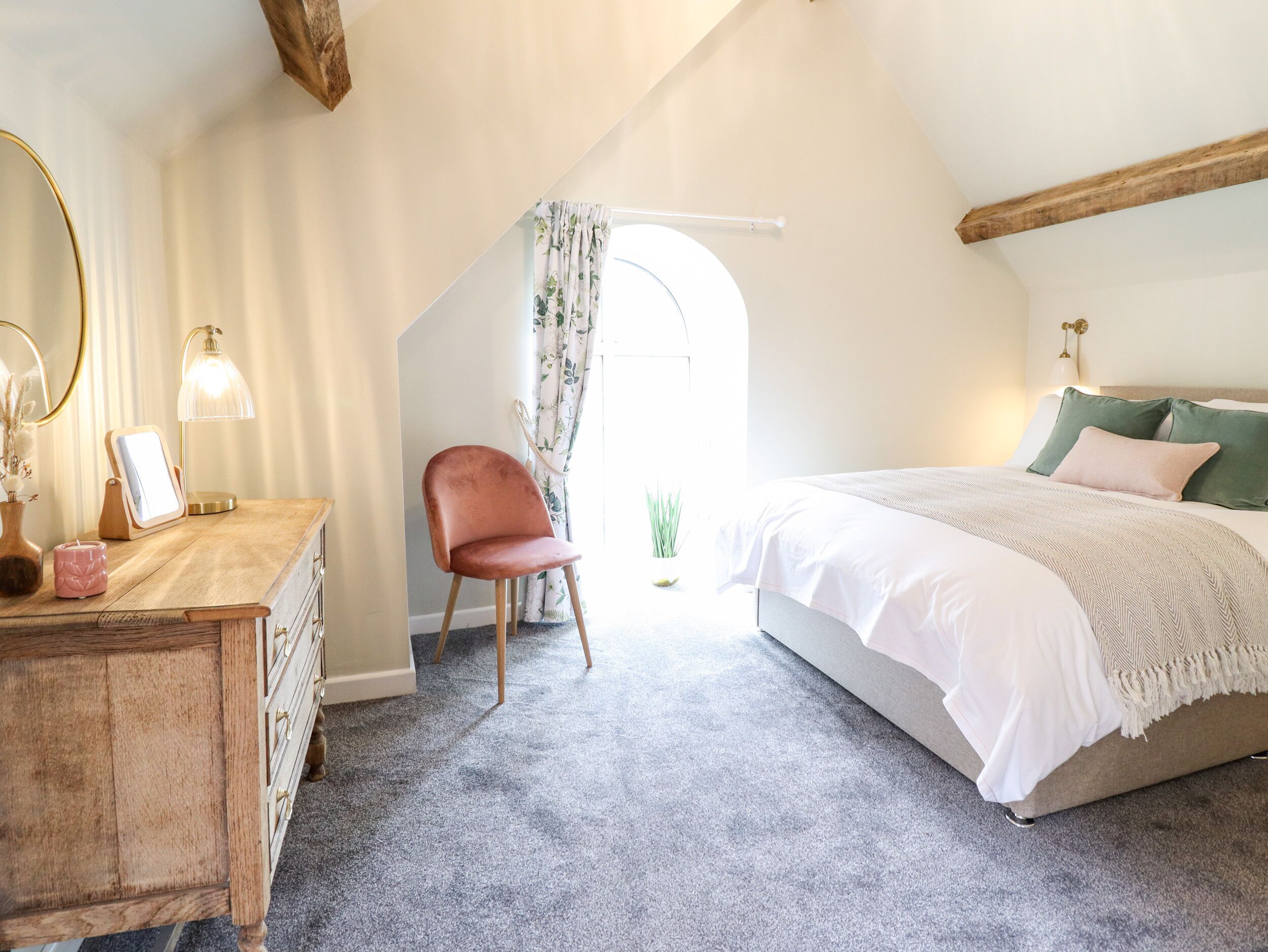 A bedroom with a bed, a chair, a dresser, and a mirror.