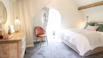 A bedroom with a bed, a chair, a dresser, and a mirror.