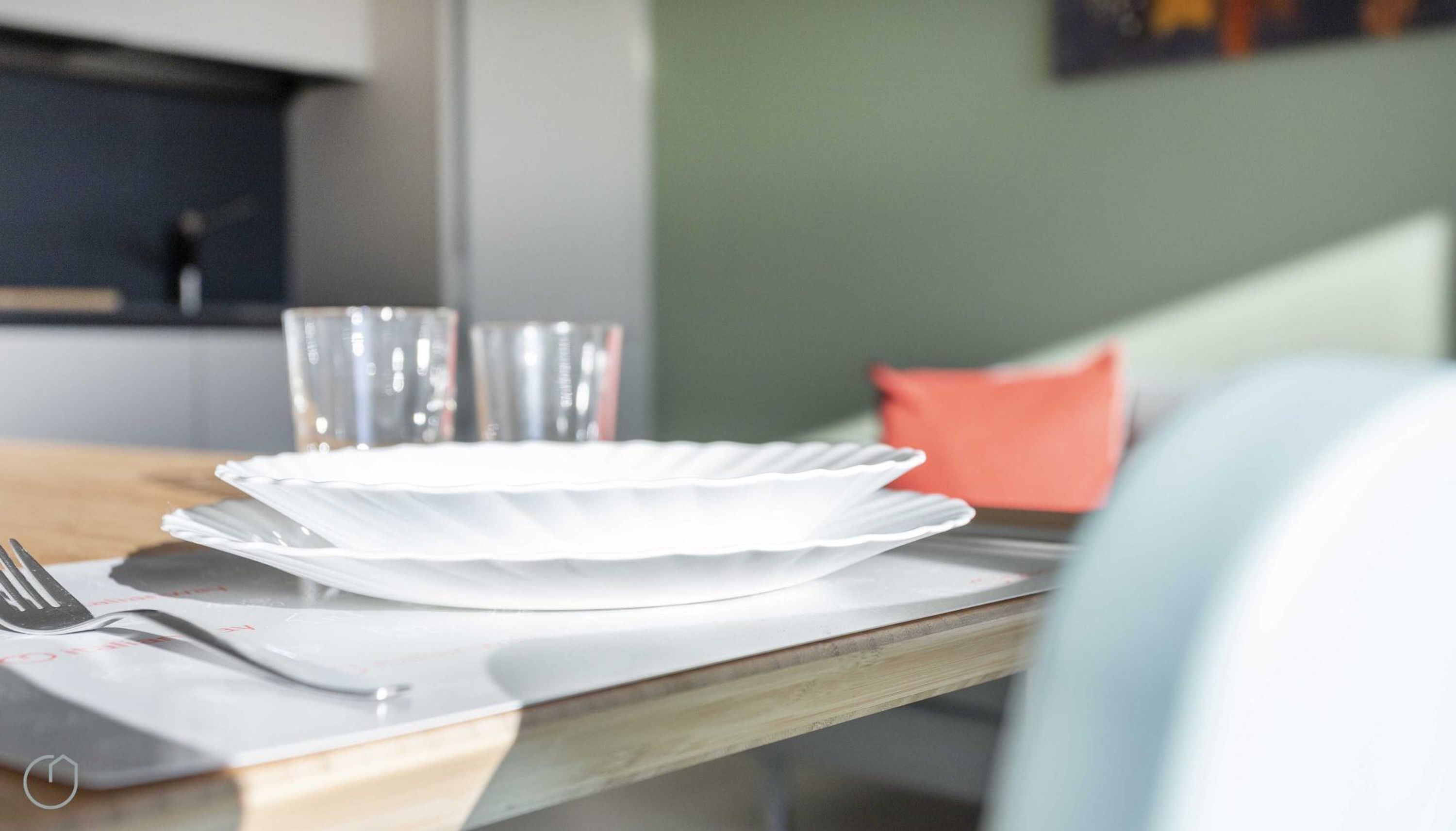 A dining table with a white plate, a fork, and two glasses.