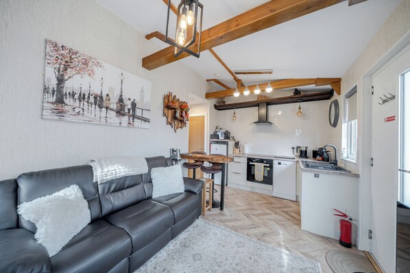 A modern kitchen with a central island, a dining area with a sofa and chairs, and a living room with a black leather sofa.