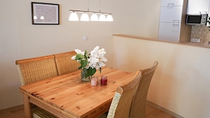 Una mesa de madera con sillas de mimbre, un jarrón con flores y velas.