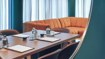 Ein Konferenzraum mit einem langen Tisch, mehreren Stühlen, einem Sofa und Blick durch große Fenster nach draußen.