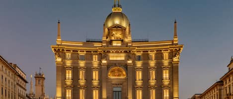 A grand building with a prominent dome and classical architecture, featuring multiple windows and a central entrance.