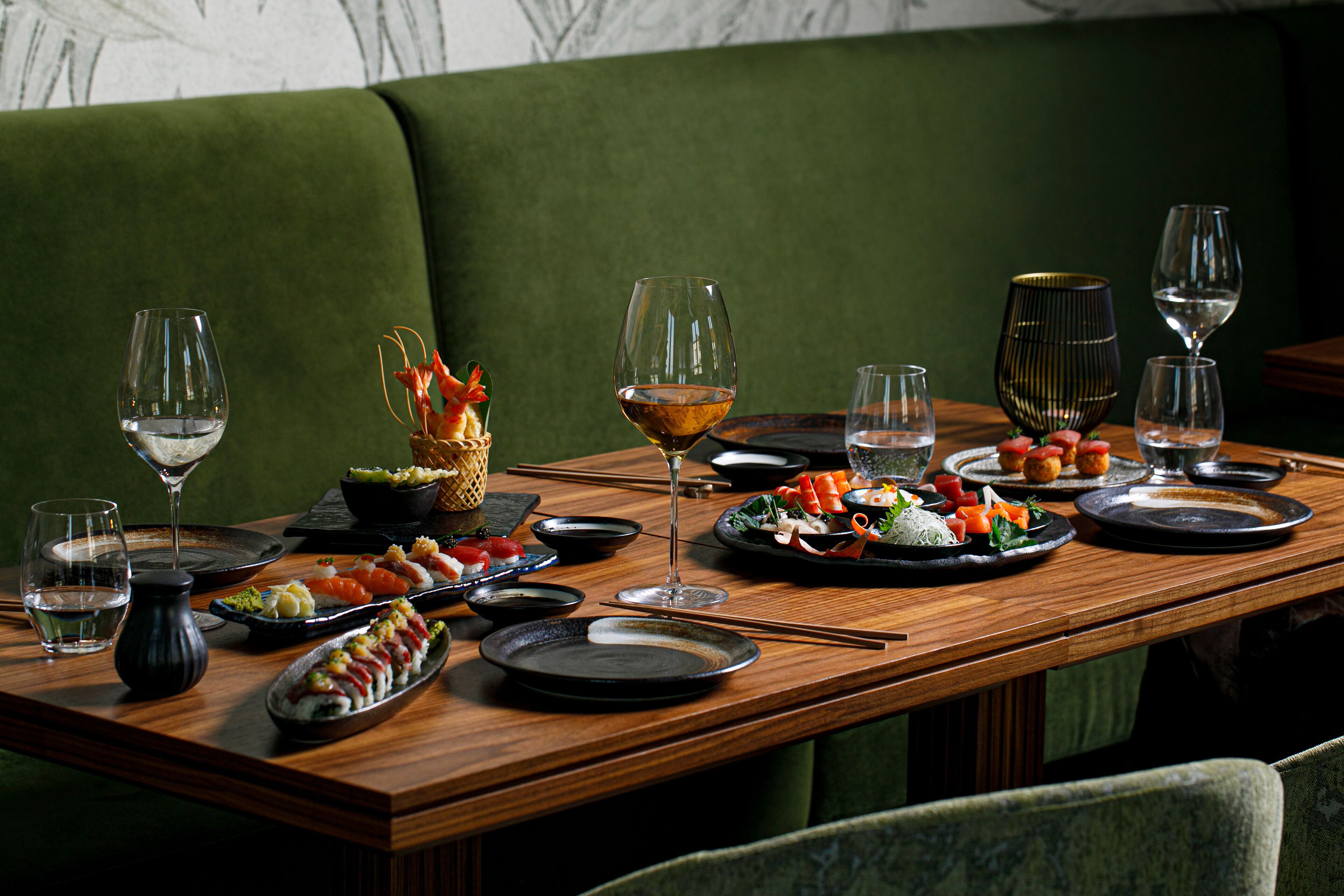 Una mesa de comedor servida con diferentes platos, vasos y palillos.