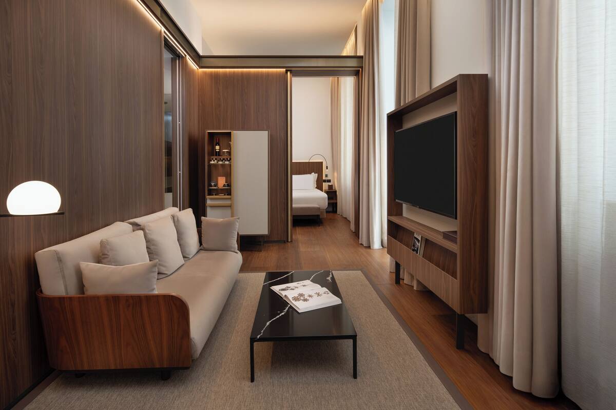 Une chambre d’hôtel moderne équipée d’un canapé, d’un téléviseur à écran plat, d’une table basse et d’un dressing.