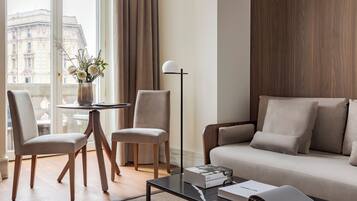 A modern living room with a sofa, two chairs, a coffee table, a floor lamp, and a vase with flowers.