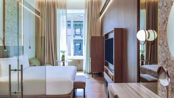 Quarto de hotel com cama grande, televisão, escrivaninha e vista para a cidade.