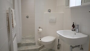 Ein Badezimmer mit Toilette, Waschbecken und Duschbereich.