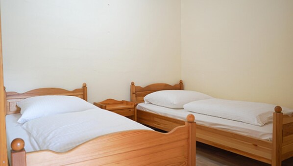 A room with two wooden beds, each with a wooden headboard and footboard, and a wooden nightstand between them. - Ferienwohnung Seestern (Fehmarn)