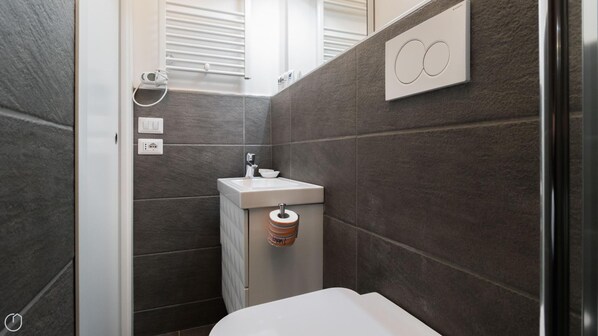 A modern bathroom with a built-in sink, a toilet, and a shower area. - Atto Vannucci 15 B (Milan)