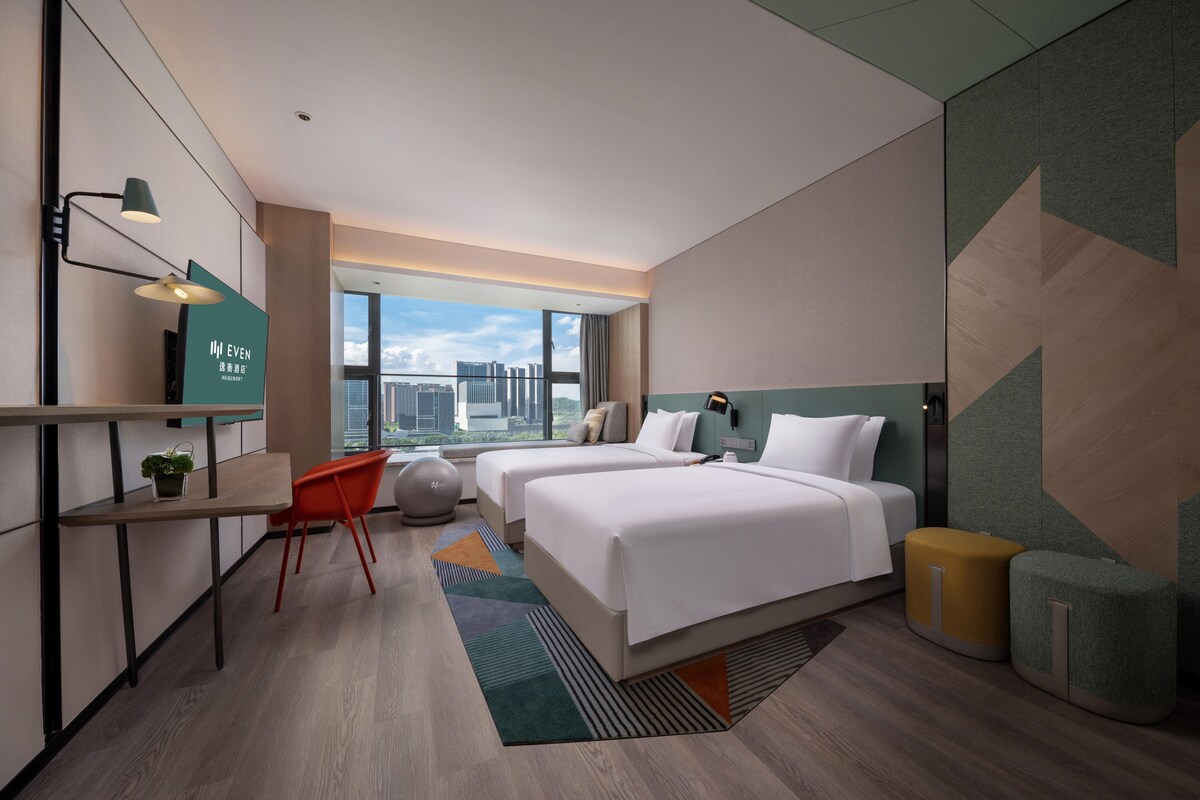 Habitación de hotel moderna con una cama grande, un escritorio y vistas a la ciudad.