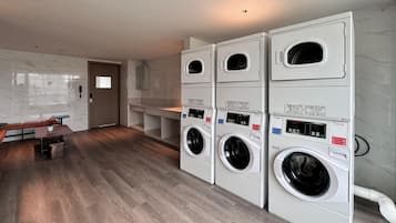 A laundry room with four stacked washing machines, a bench, and a small table.