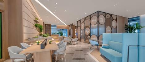 A modern hotel lobby with a long reception desk, seating area, and a blue sofa.