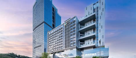 Et moderne hotel med en markant glasfacade, flere etager og et unikt arkitektonisk design.