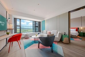 A modern hotel room with a large window, a sofa, a chair, a small table, and a bed. - Even Shenzhen Guangming Cloud Park (Shenzhen)
